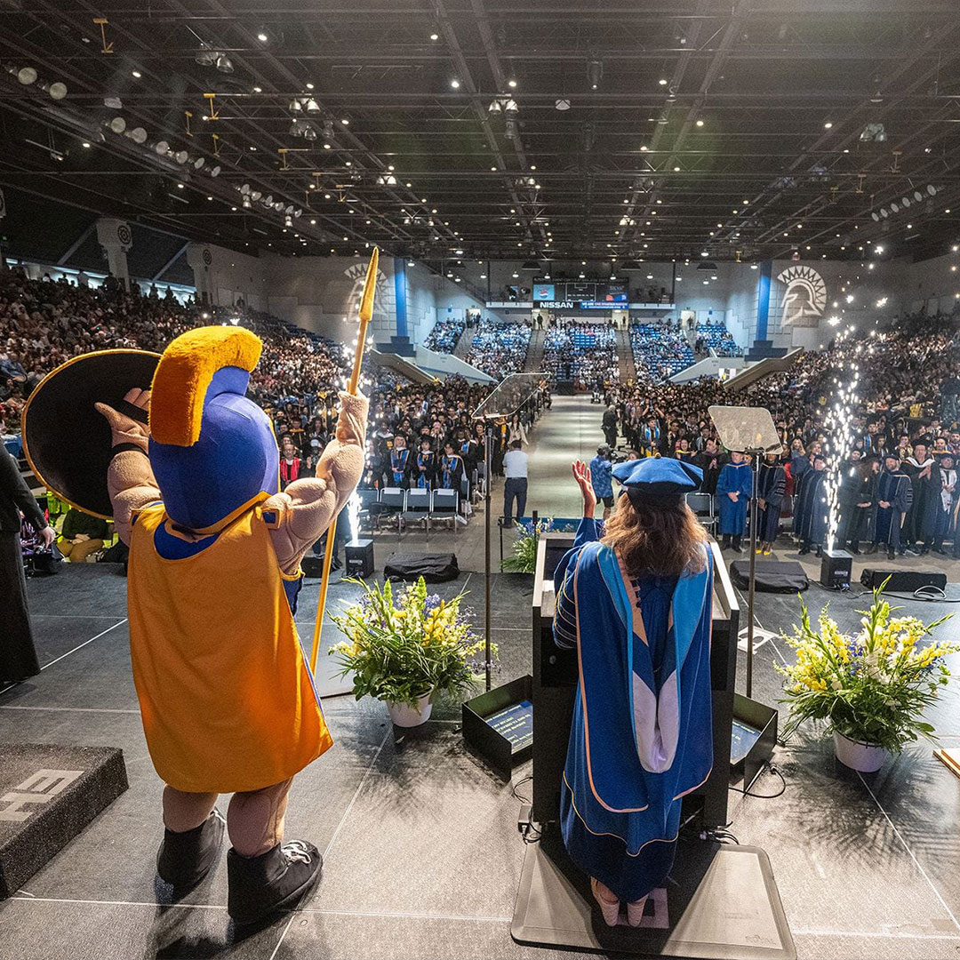 President Matson with Sammy Spartan on Stage at Commencement facing Graduates who are celebrating. Photo by Robert C. Bain.
