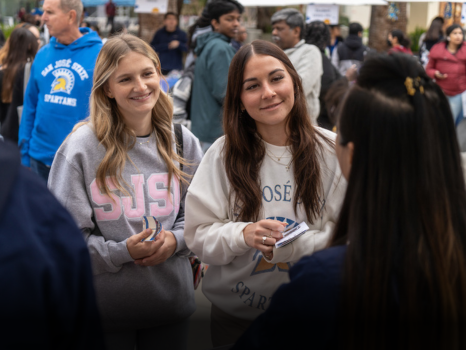 Two students speaking with college vendor.