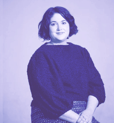 a photo of a woman with dark hair and a fuzzy sweater sitting in front of a white background