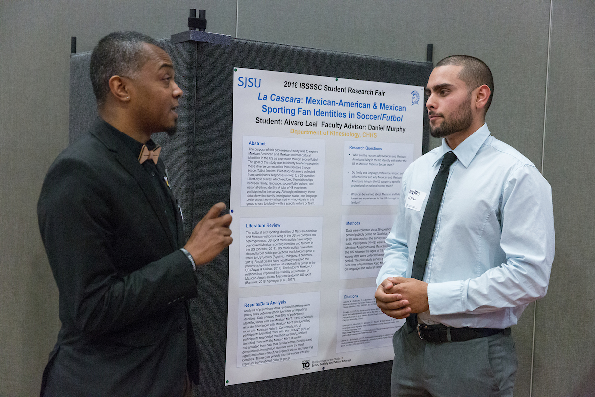 Two students talk in front of a research poster.