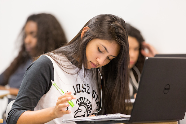 student sitting on desk working on a laptop