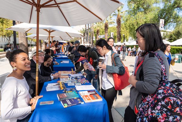 woman at recruiting table with students surrounded