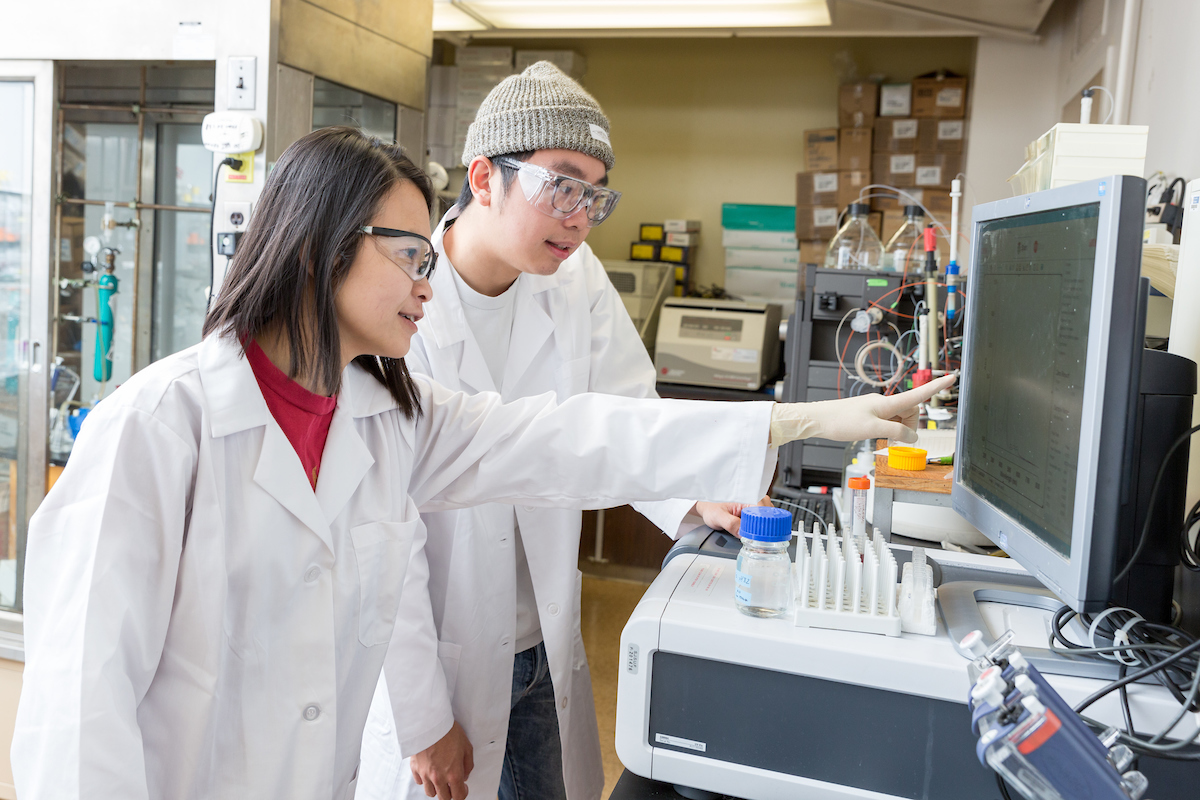 student and professor pointing in a lab