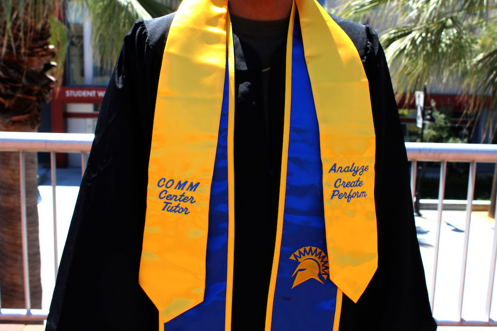 student wearing a satin yellow COMM Center graduation stole