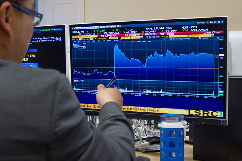 Business student pointing to a computer screen with data.