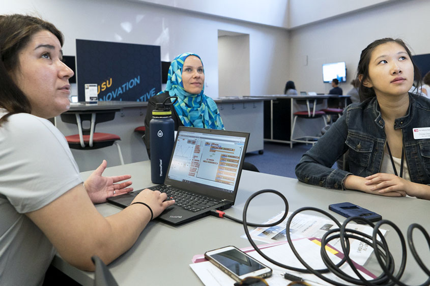 Students sitting around a table with their laptops.