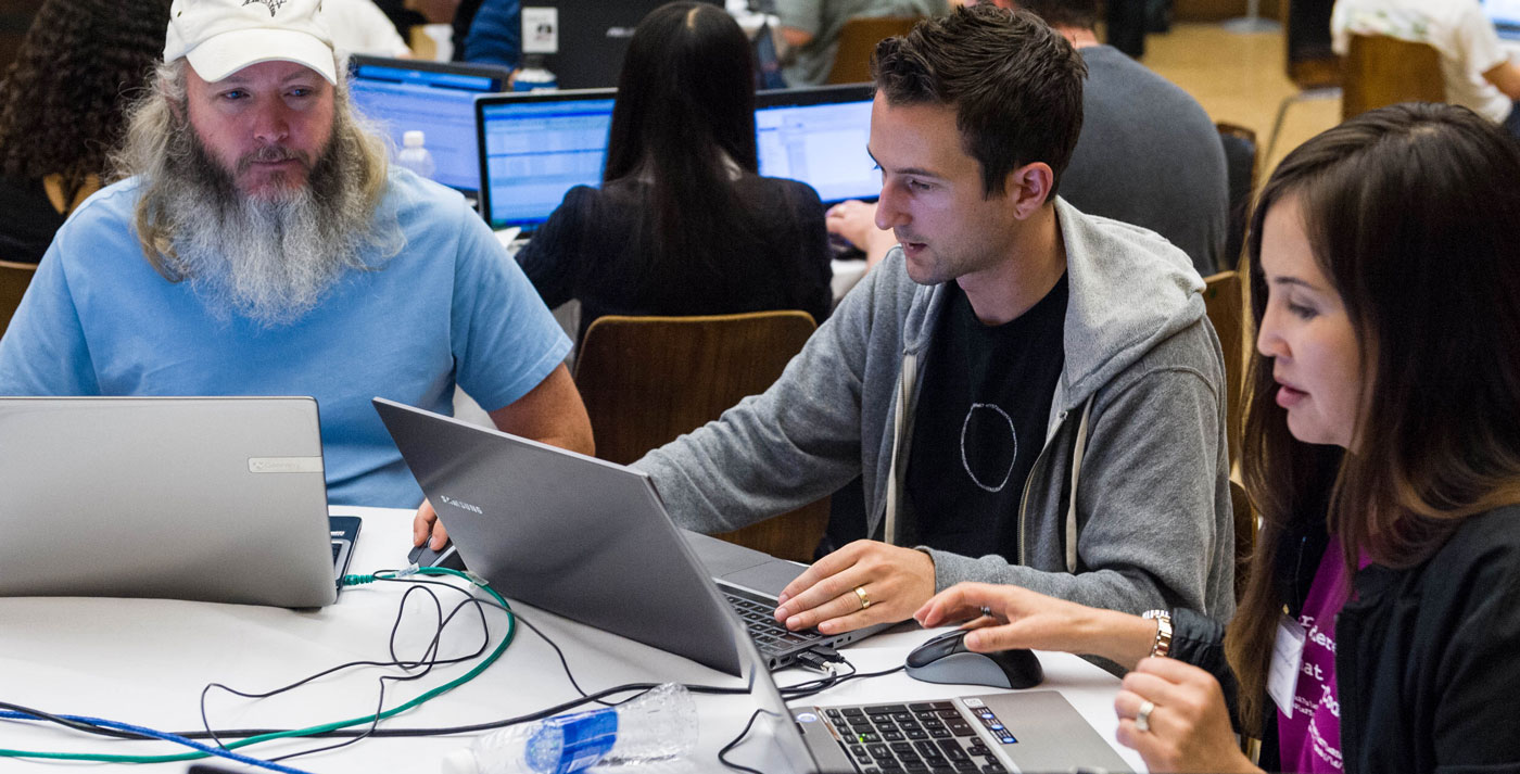 Three students working together on their laptops.