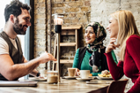 Three people drinking coffee at a table.