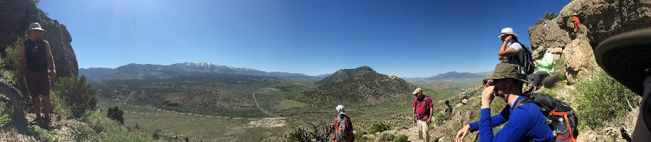A group of geology students on a rocky mountain, looking out into a valley
