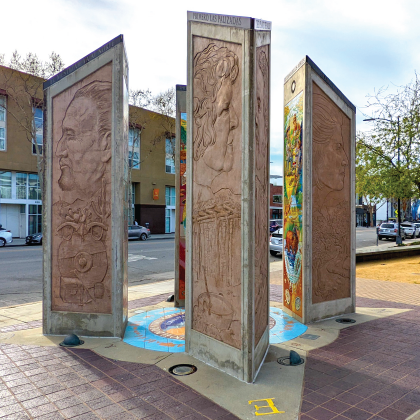 three obelisks of stone with images outdoors in sunshine.