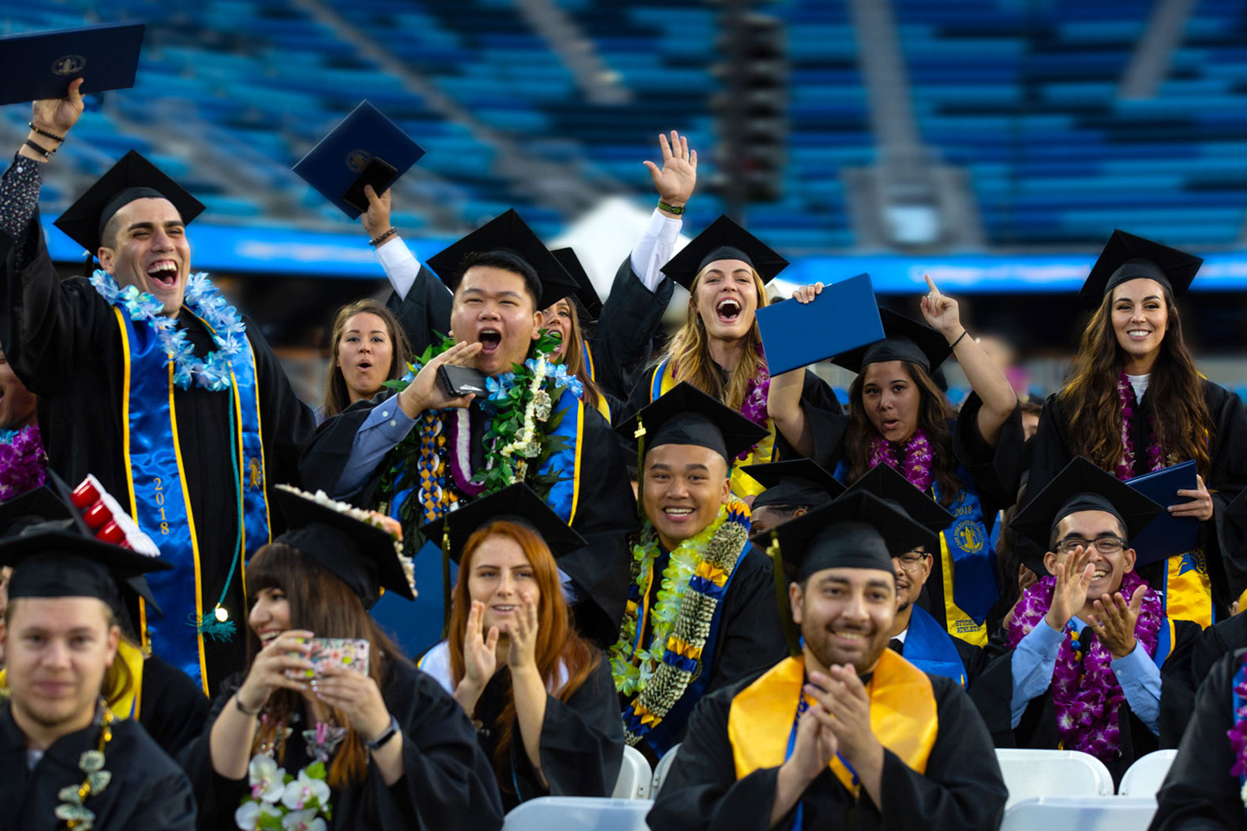 Graduates cheering in their caps and gowns.