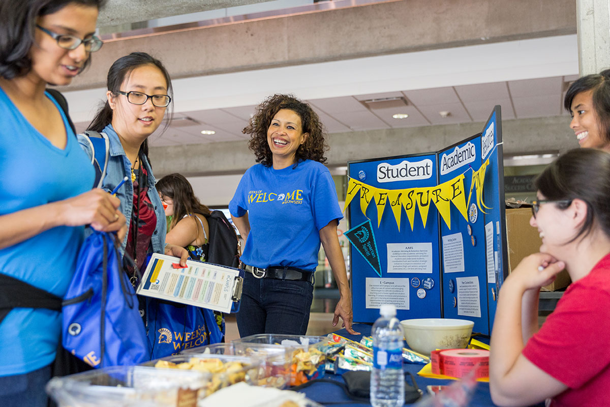 Staff member smiling in front of a WOW booth with students.