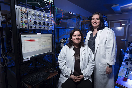 serena ortiz and mentor stand in lab coats in front of biology equipment