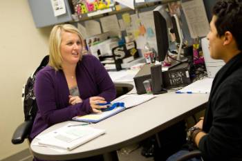 Image of a student and an advisor sitting at a desk and talking.