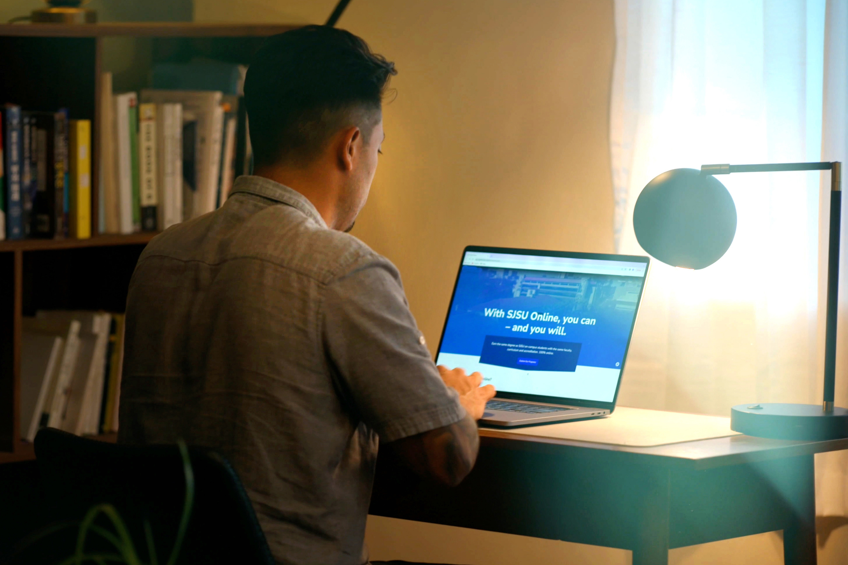 Man looking at the SJSU Online homepage on his laptop.