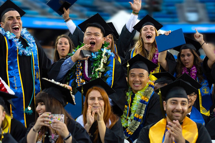 Happy SJSU graduates cheering and celebrating together at their graduation ceremony