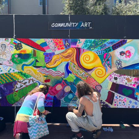 student and artist painting a mural