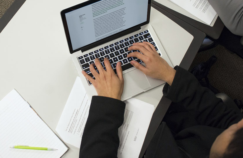 Student typing on their laptop.