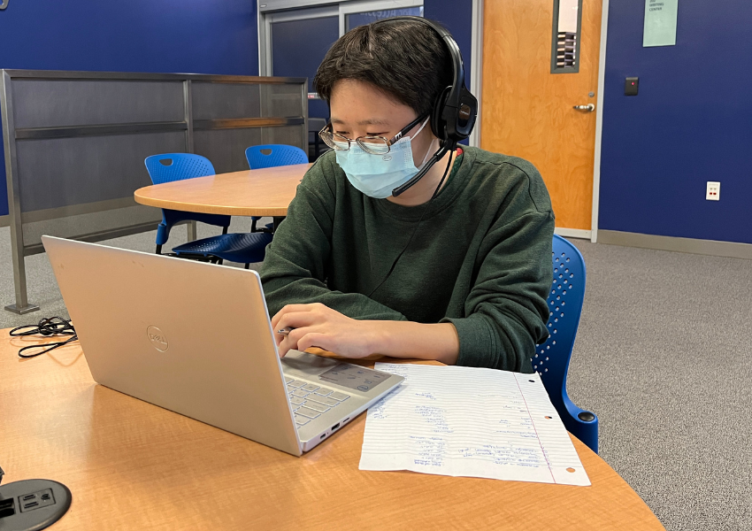 Tutor with headphones sitting in front of laptop